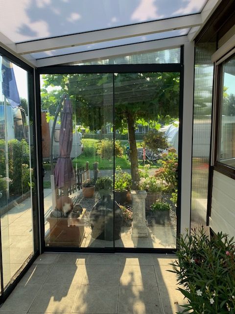 Een kamer met veel ramen en uitzicht op een tuin