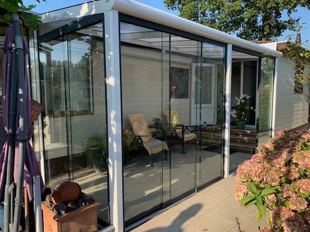 Een patio met glazen schuifdeuren en een wit huis op de achtergrond.