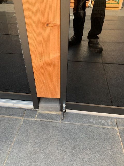 Een persoon staat voor een houten deur