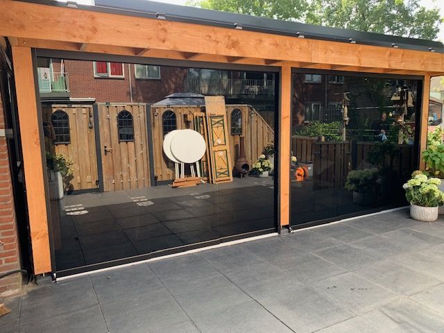 Een terras met een glazen schuifdeur die lijkt op een garagedeur.