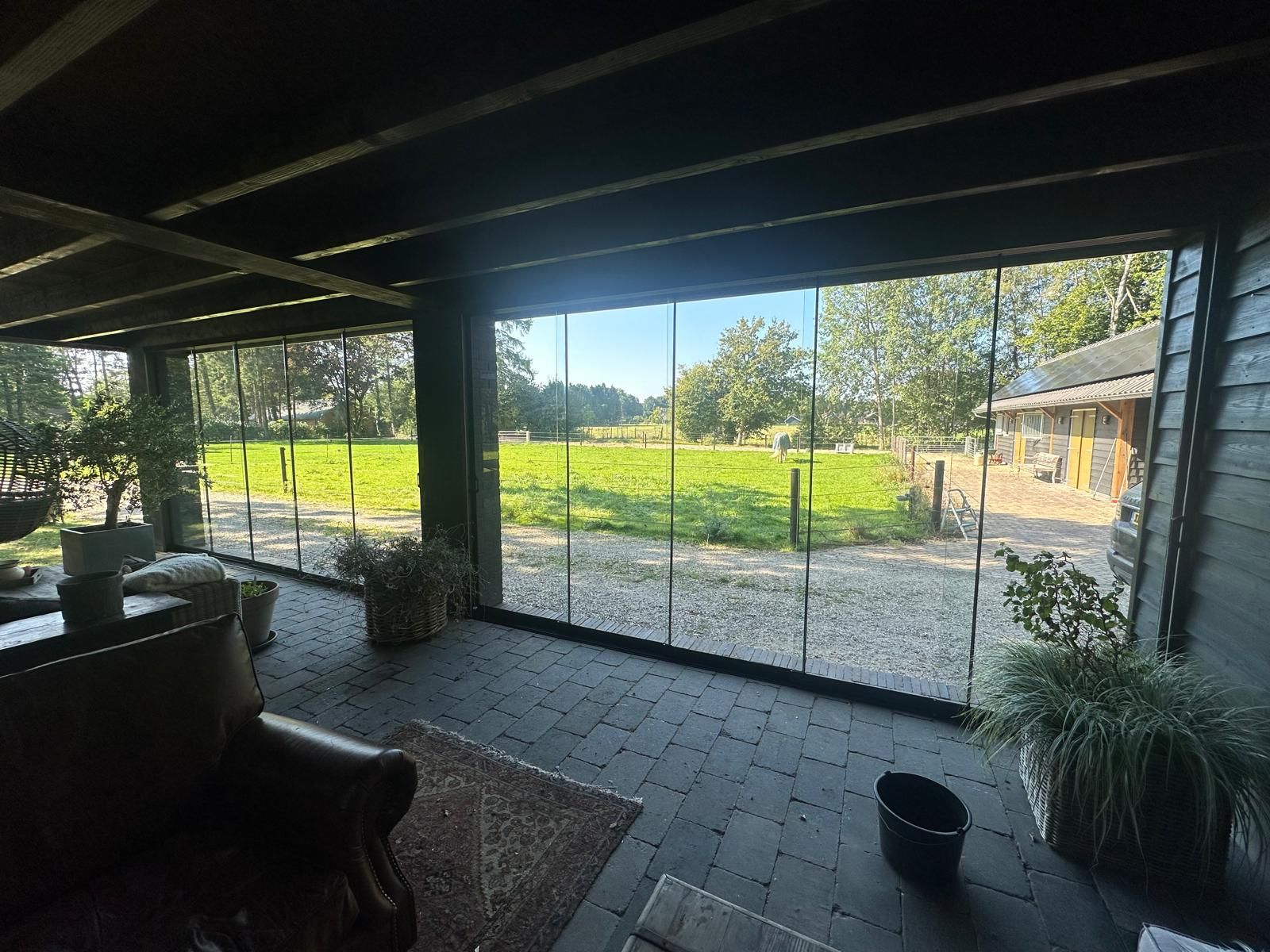 Een woonkamer met veel ramen en uitzicht op een veld.