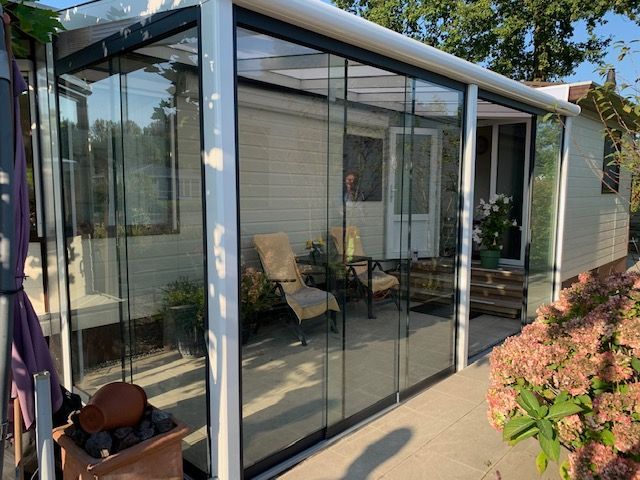 Een patio met glazen schuifdeuren en een wit huis op de achtergrond.