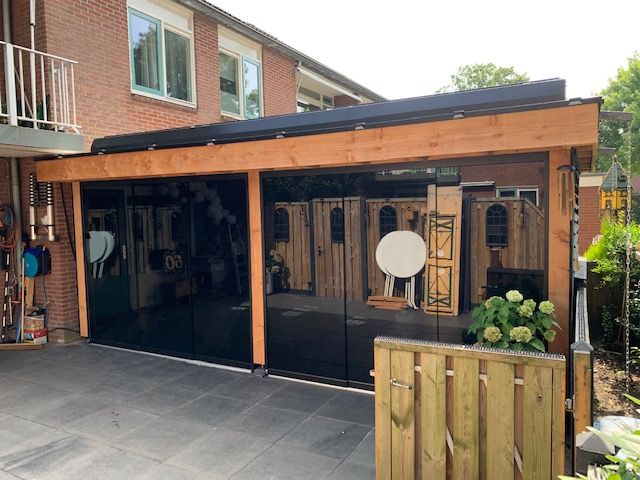 Een bakstenen huis met een houten veranda en glazen schuifdeuren.