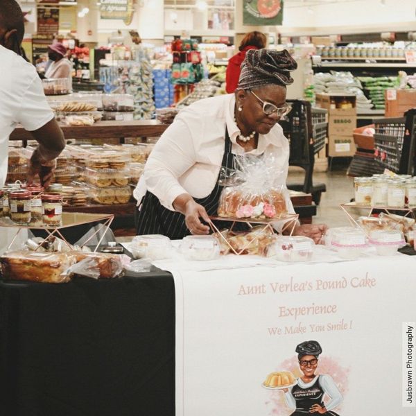 A woman is cutting a cake at aunt vernon 's food cafe