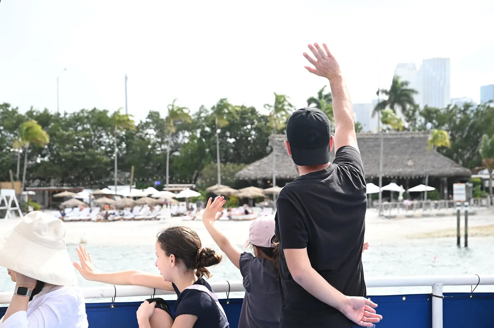 family enjoying a boat tour in Miami on Biscayne Bay with kids waving during sightseeing cruise