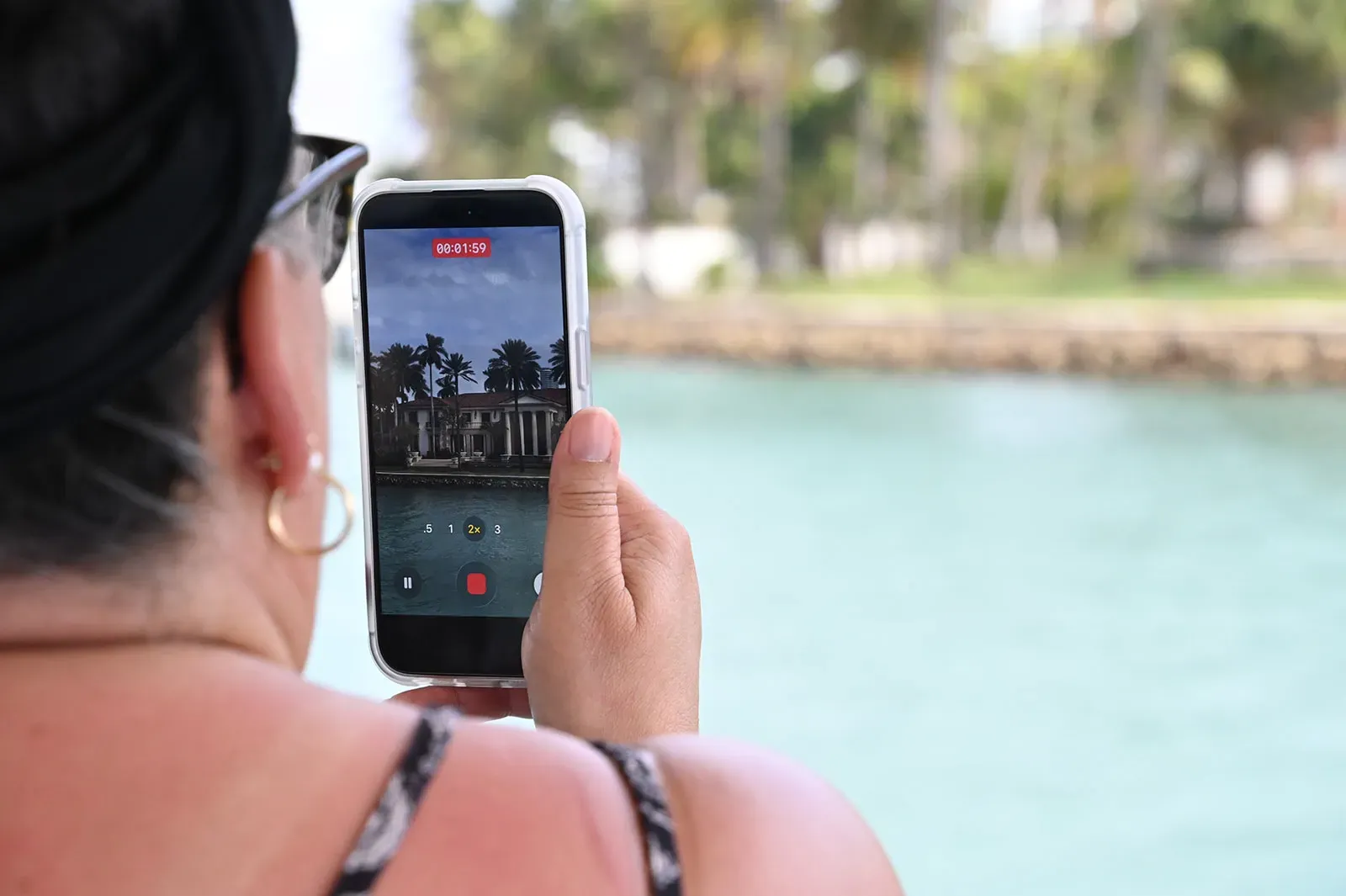 Guest taking photos of celebrity homes on a Miami boat tour in Biscayne Bay