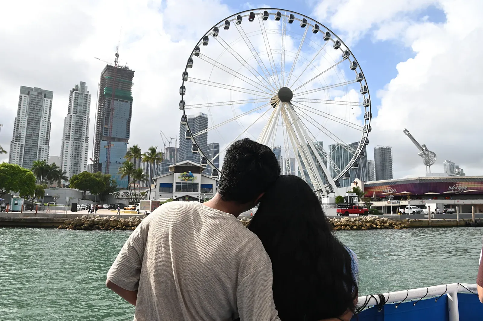couple enjoying a Miami boat tour with skyline and Skyviews ferris wheel on Biscayne Bay