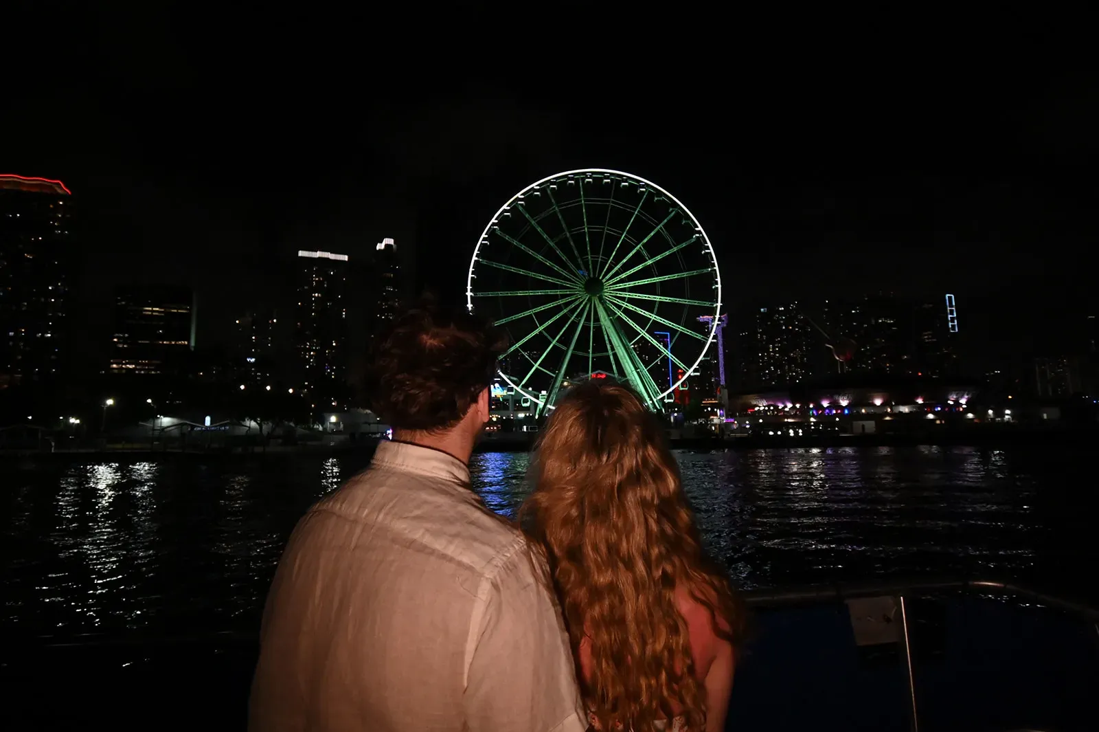 couple enjoying a Miami night boat tour with skyline and ferris wheel views on Biscayne Bay