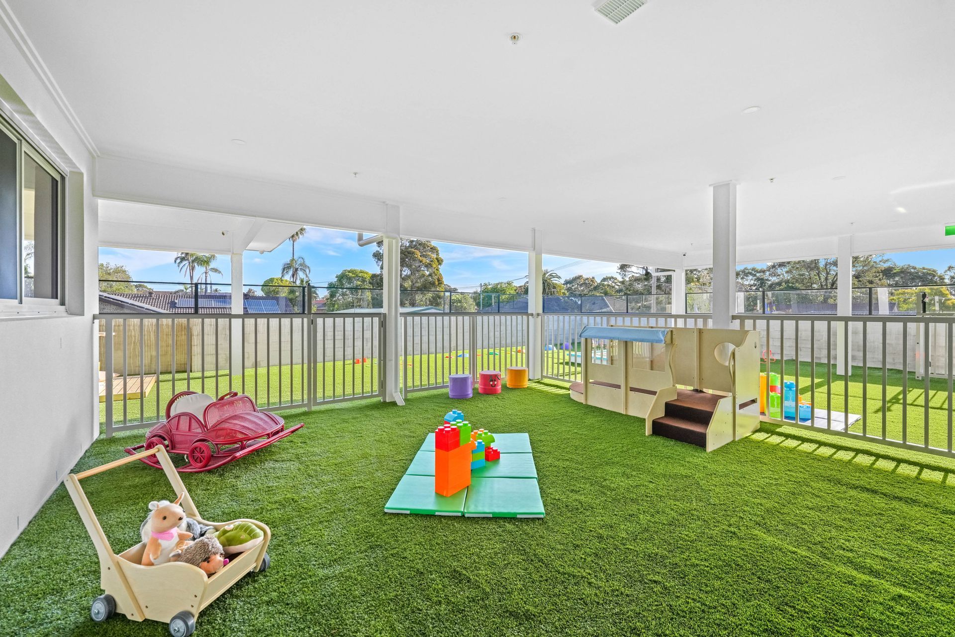 Play area with artificial turf, toys, and a fenced perimeter.