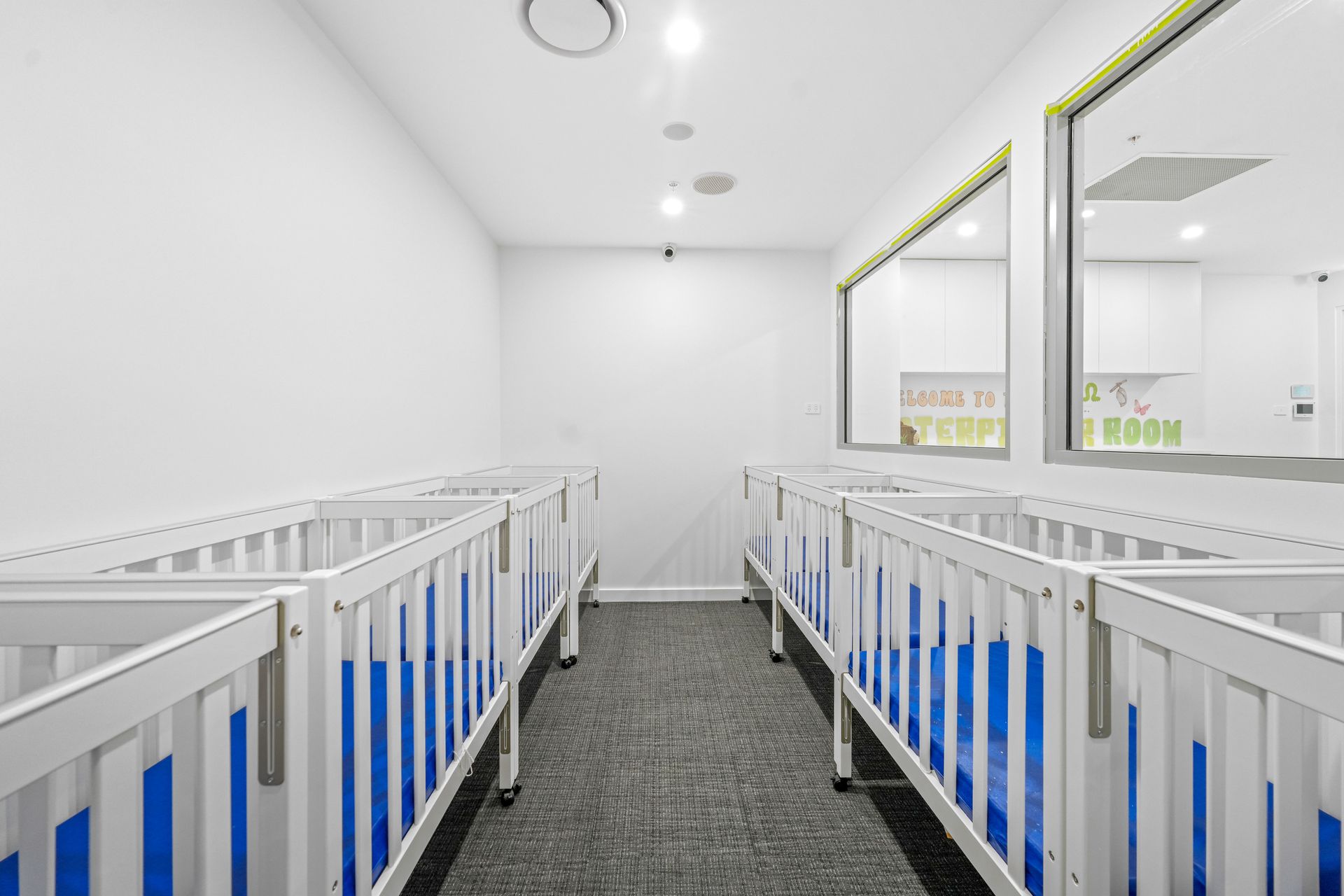 Cot room in a bright, modern nursery room with blue bedding. 