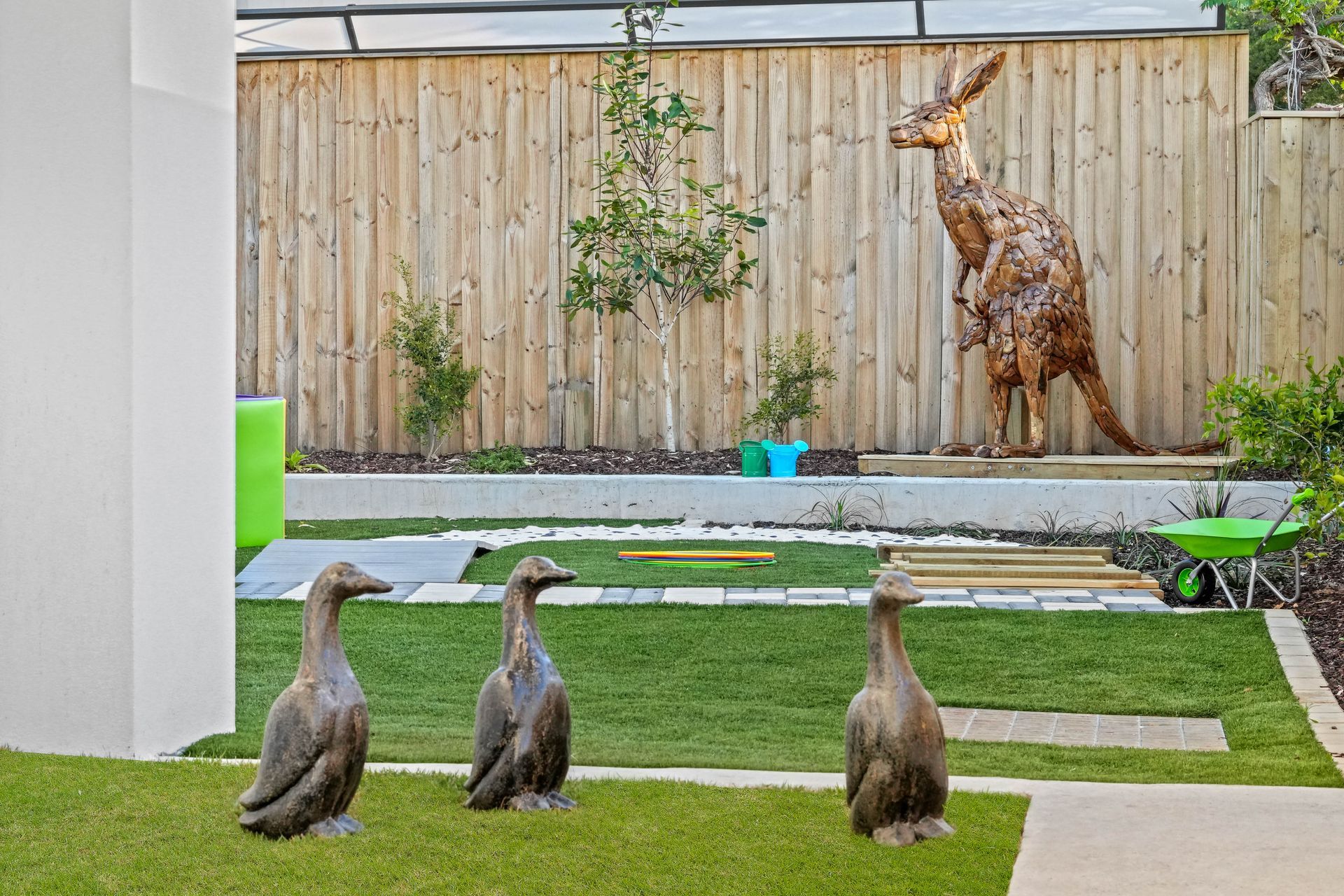Three duck statues on lawn, kangaroo sculpture in a backyard.