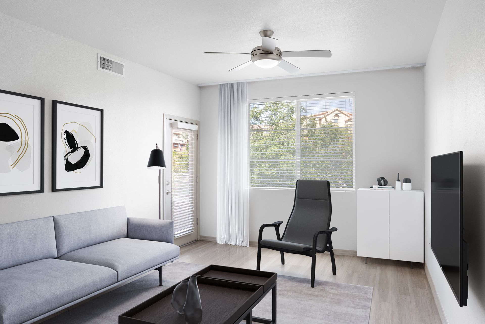 Living room in a modern apartment with a gray sofa, black lounge chair, coffee table, and a large window.
