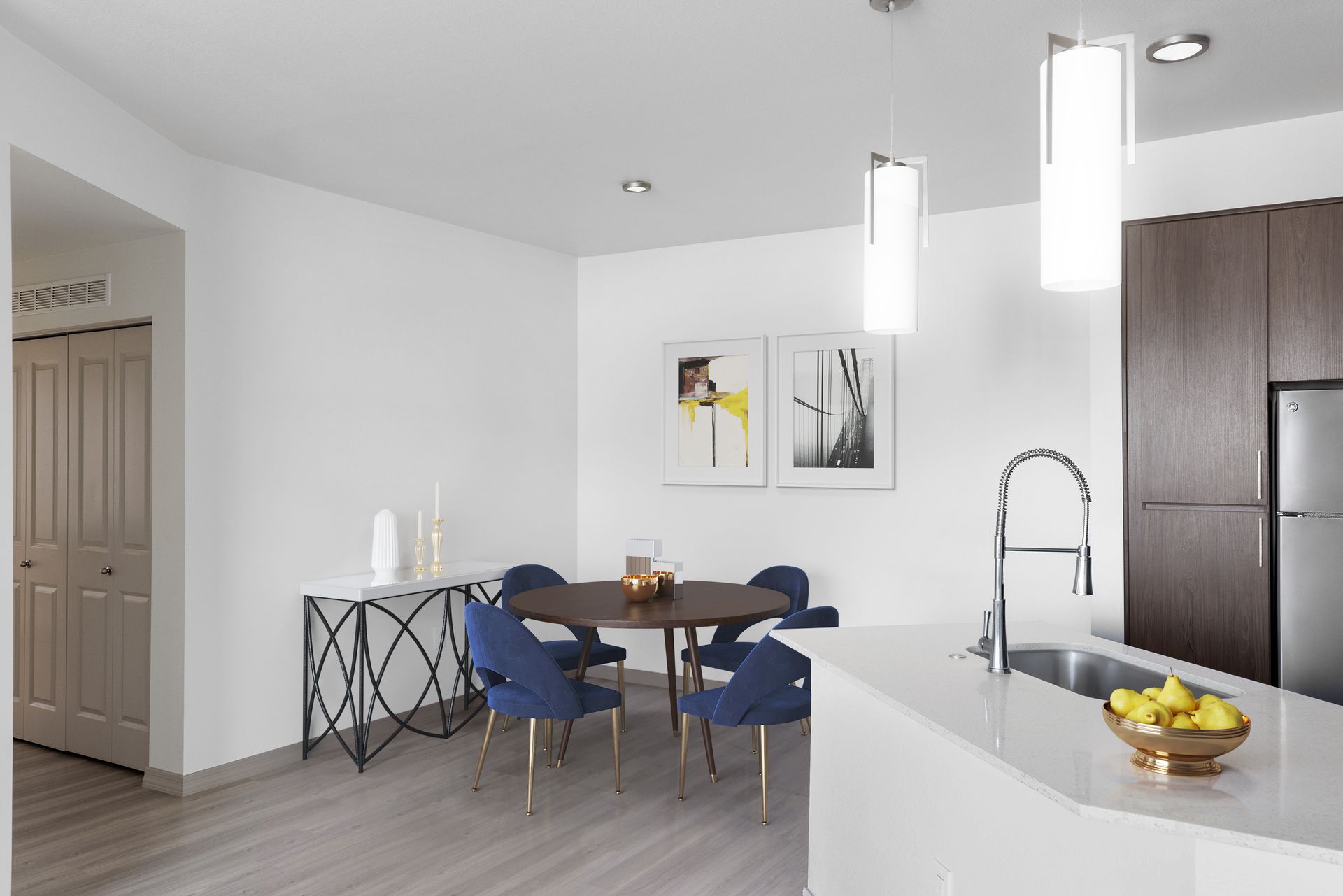 Open-concept kitchen and dining area with a round table and blue chairs.