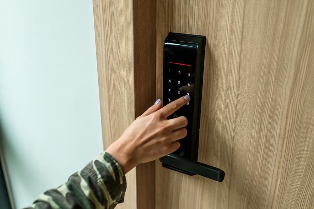 A Woman is Pressing a Button on a Door Lock — Coast & Hinterland Mobile Locksmiths In Noosaville, QLD