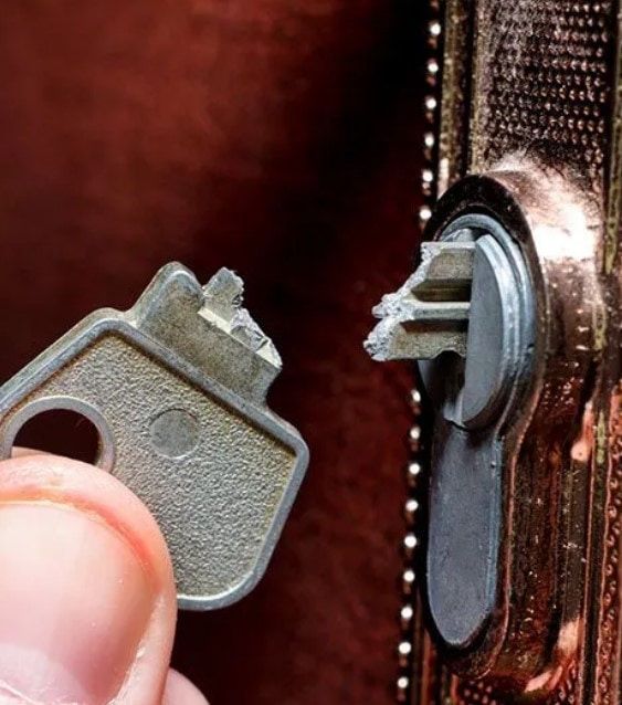 A Person is Holding a Key in Front of a Door Lock — Coast & Hinterland Mobile Locksmiths In Cooroy, QLD