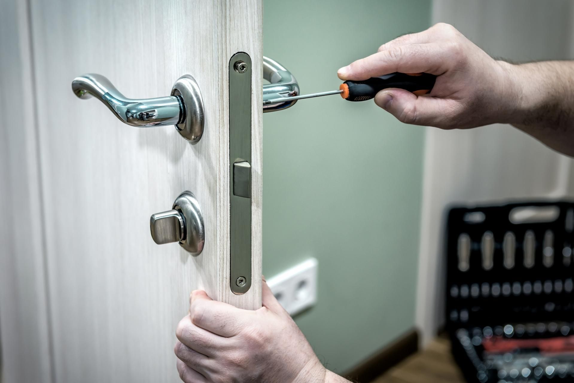 A Person Is Fixing a Door with A Screwdriver — Coast & Hinterland Mobile Locksmiths In Noosaville, QLD
