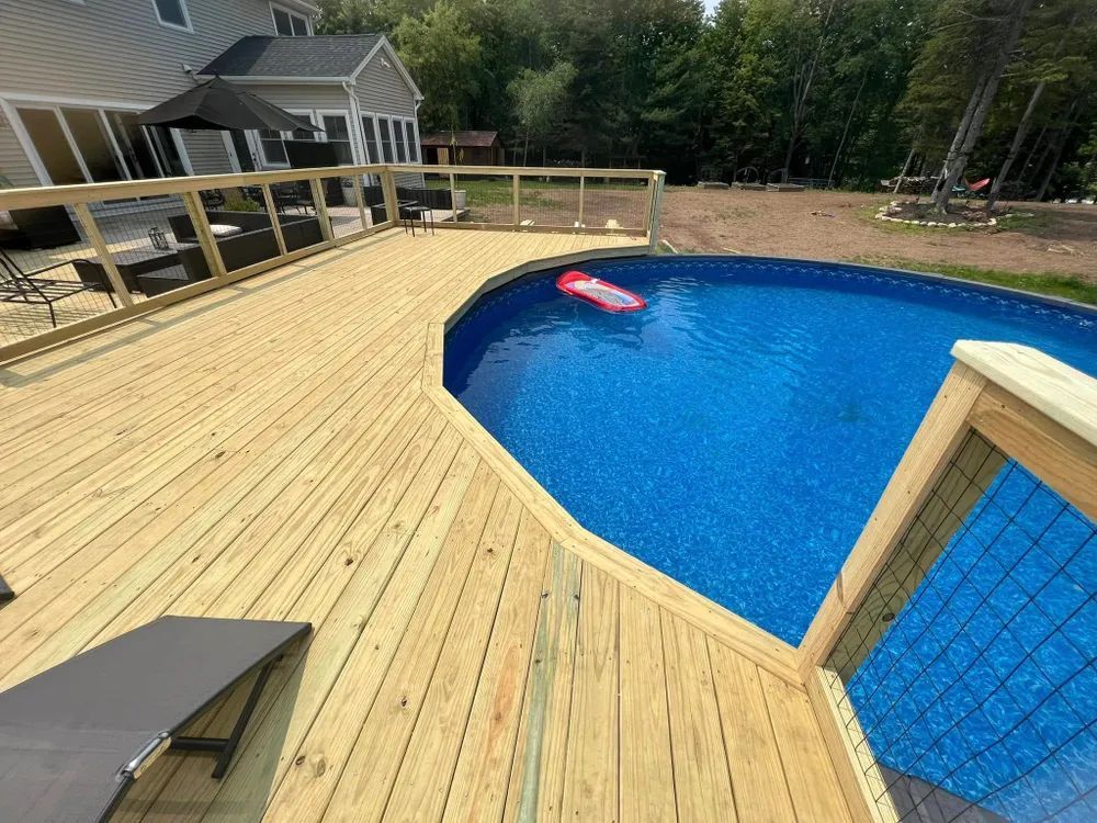 A wooden deck with a swimming pool in the background.