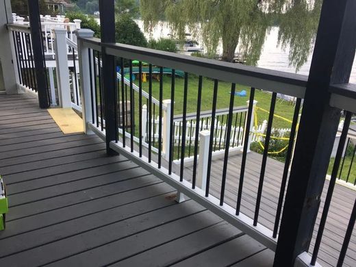 A deck with a railing and a view of a lake.