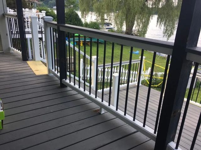 A deck with a railing and a view of a lake.