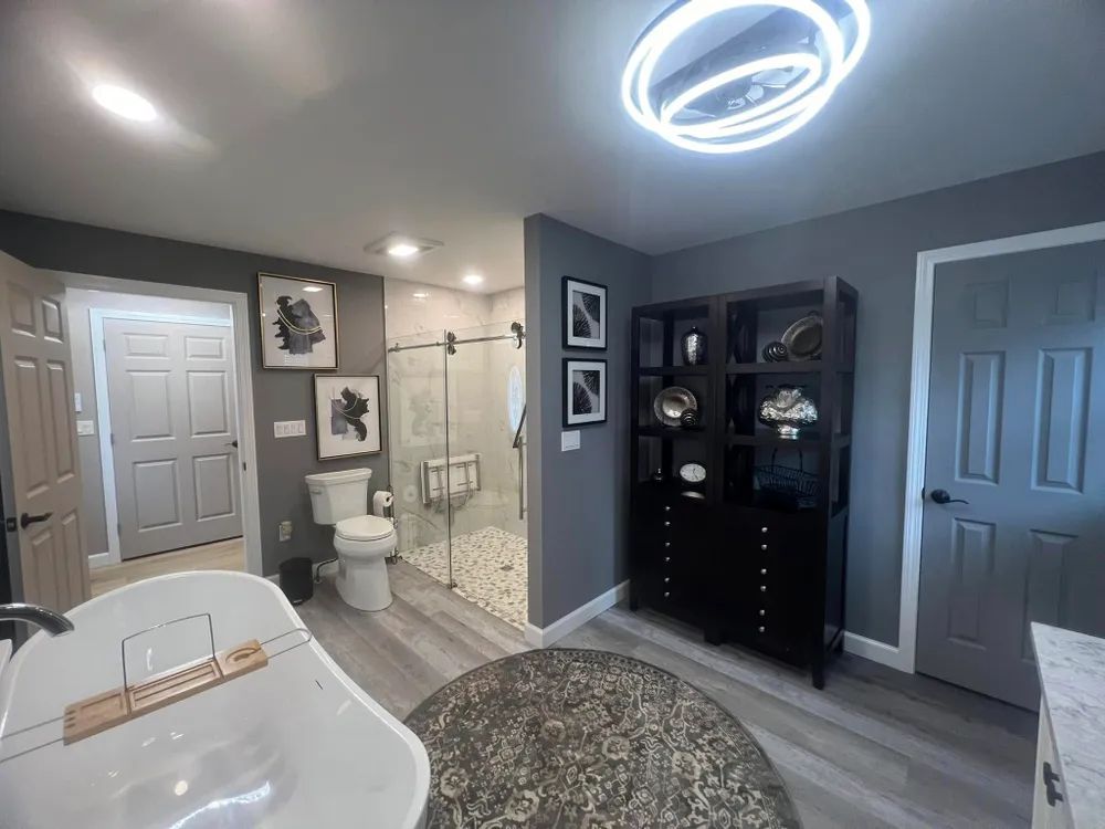 A bathroom with a tub , toilet , shower and dresser.