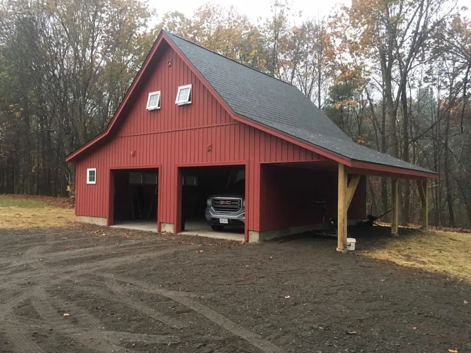 A red barn with a car parked underneath it