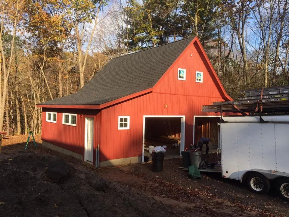 A red barn with a white trailer parked in front of it