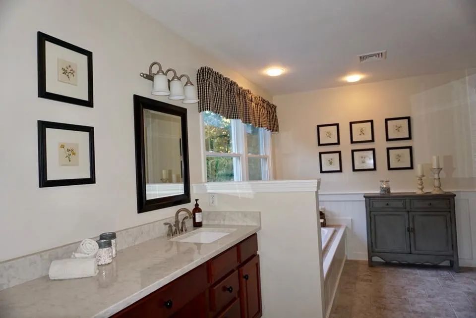 A bathroom with a sink , mirror , and bathtub.