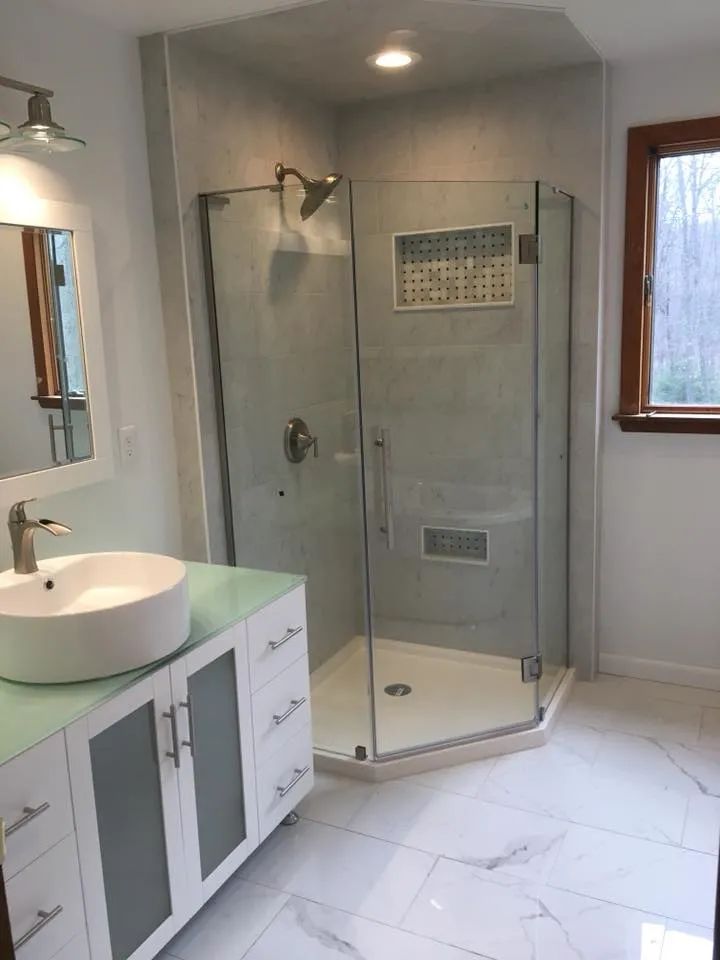 A bathroom with a sink and a walk in shower.