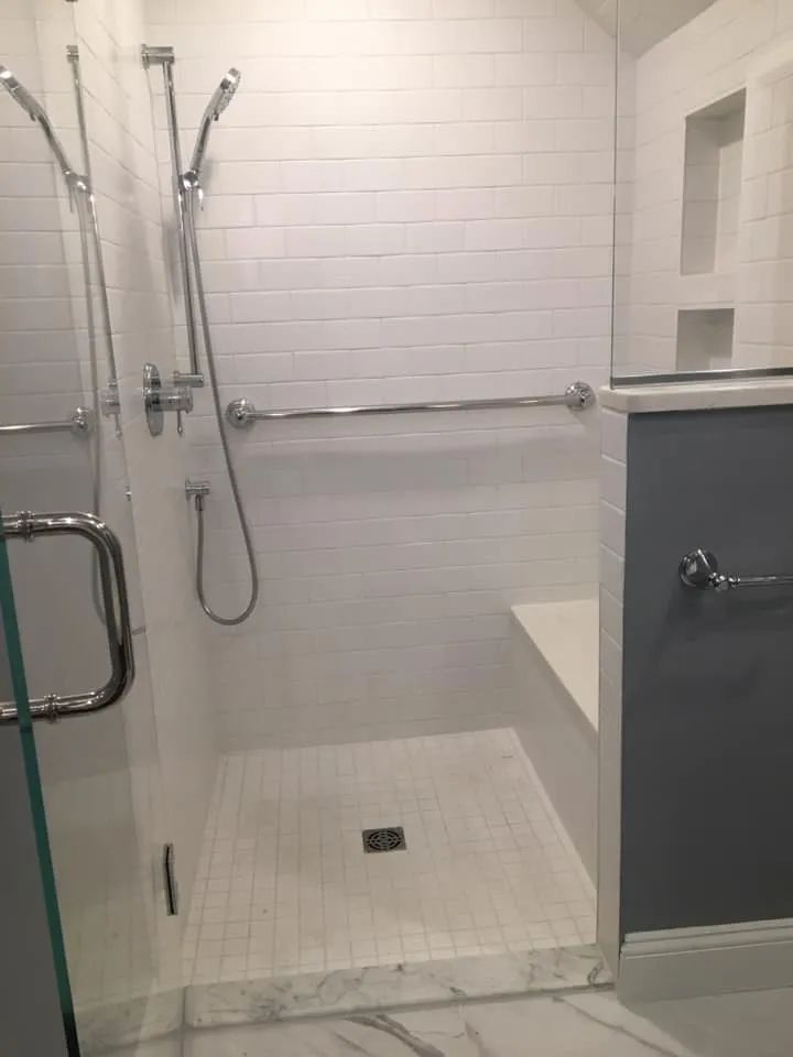 A bathroom with a walk in shower and a bench.