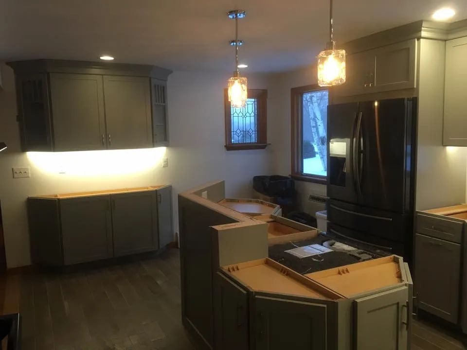 A kitchen with gray cabinets and a black refrigerator