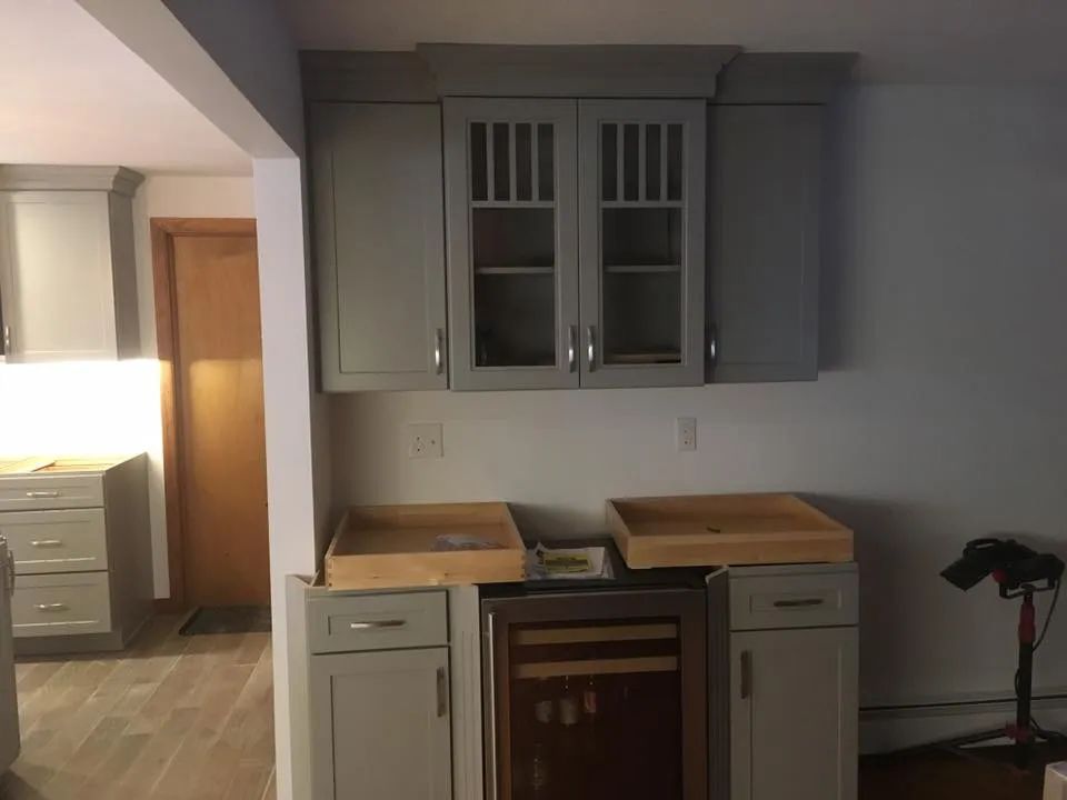 A kitchen with gray cabinets and a wine cooler