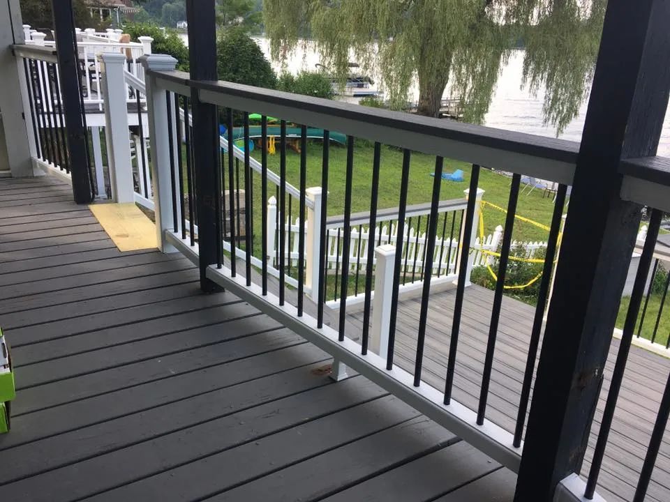 A deck with a railing and a view of a lake.