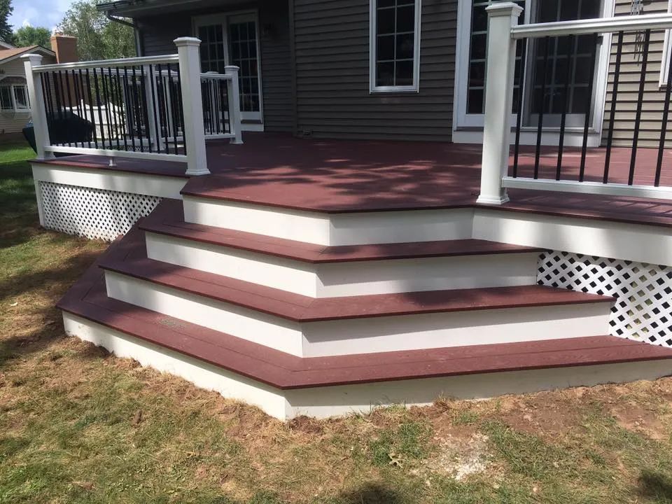 A deck with stairs leading up to it and a house in the background.