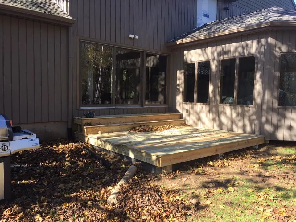 A wooden deck is being built in front of a house.