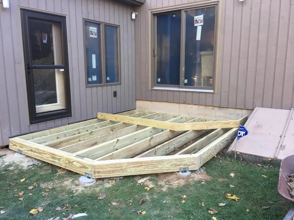 A wooden deck is being built in the backyard of a house.
