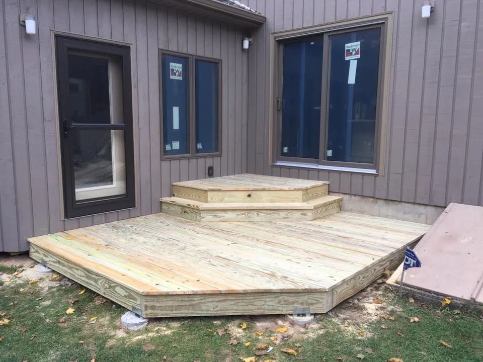 A wooden deck is being built in the backyard of a house.