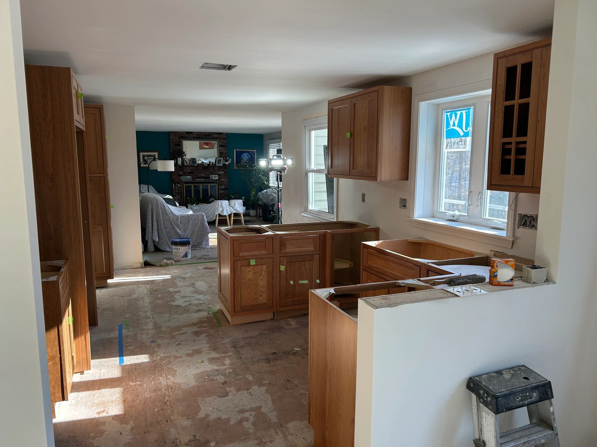 A kitchen under construction with wooden cabinets and a ladder.