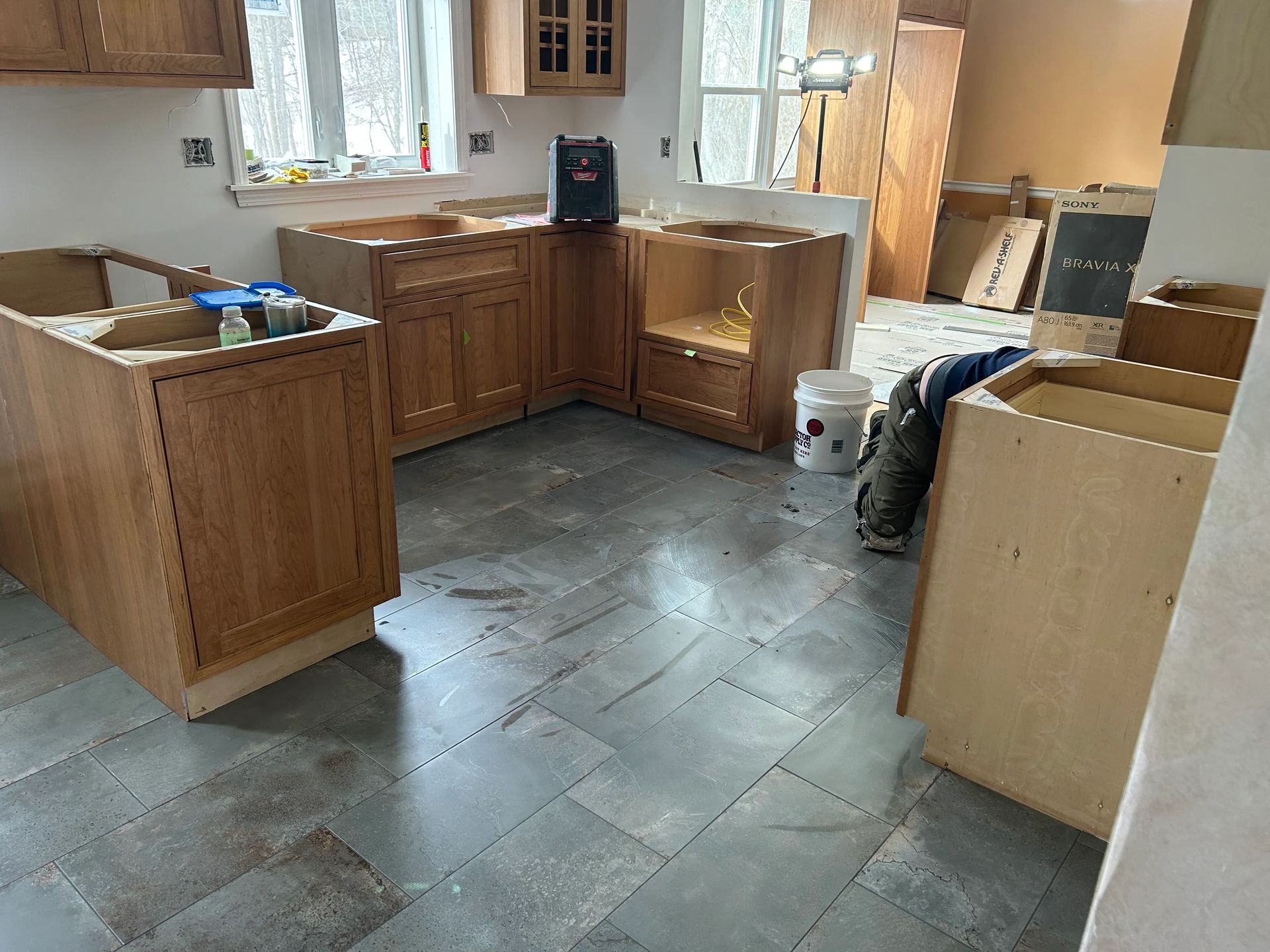 A kitchen under construction with wooden cabinets and tile floors.
