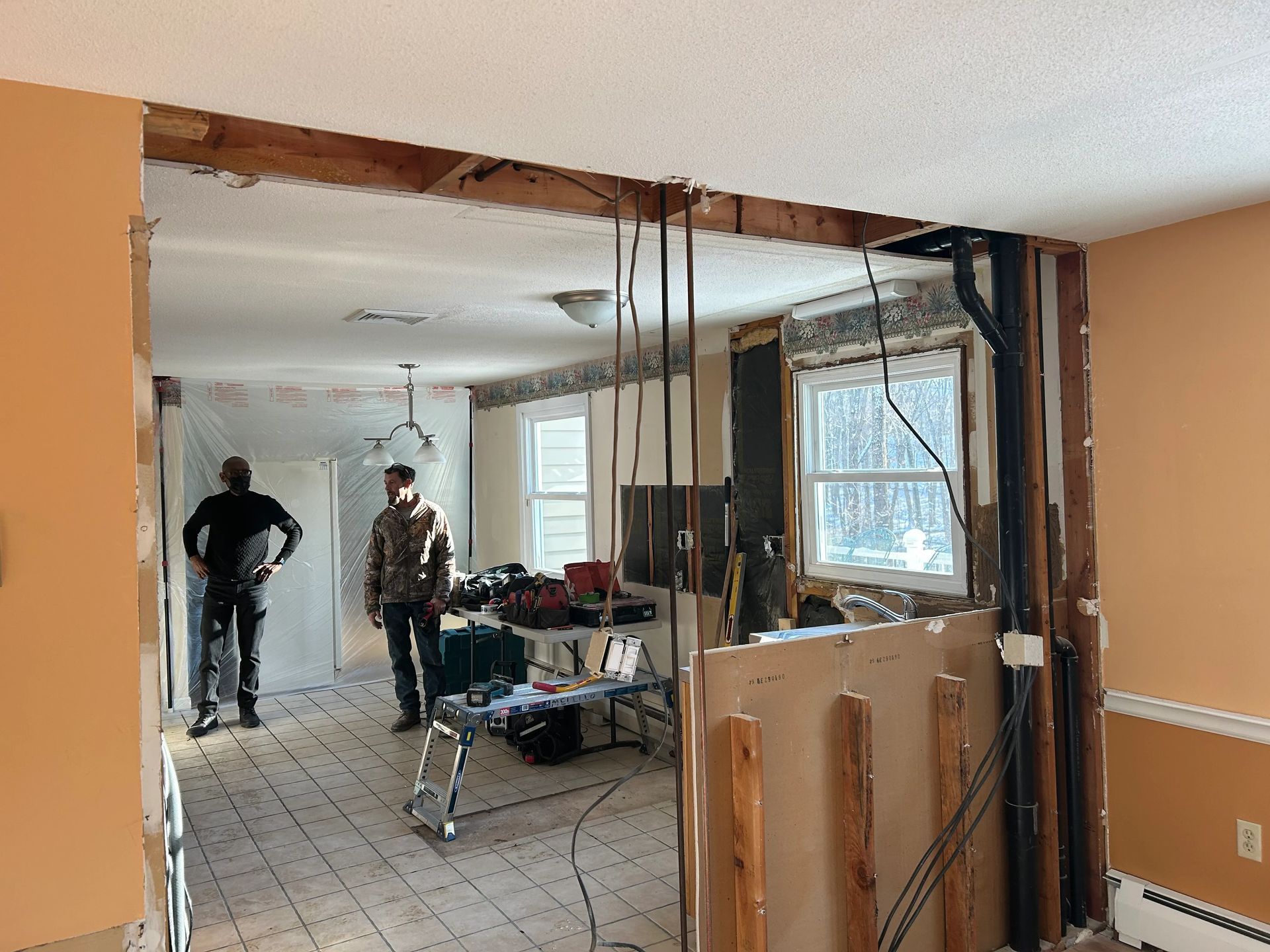 A man is standing in a room with a hole in the ceiling.