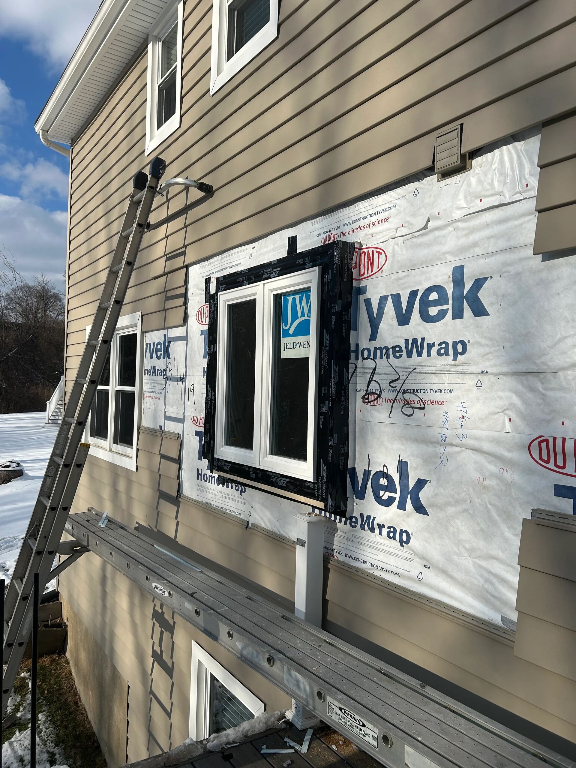 A house with a ladder attached to the side of it is being remodeled.