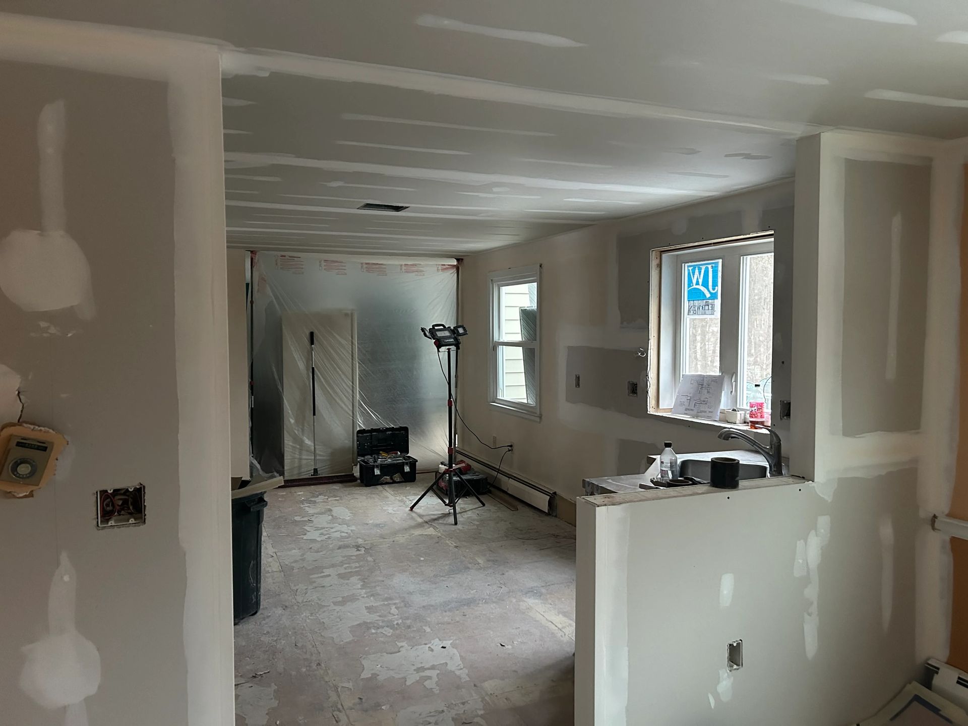A room that is being remodeled with drywall on the walls and ceiling.