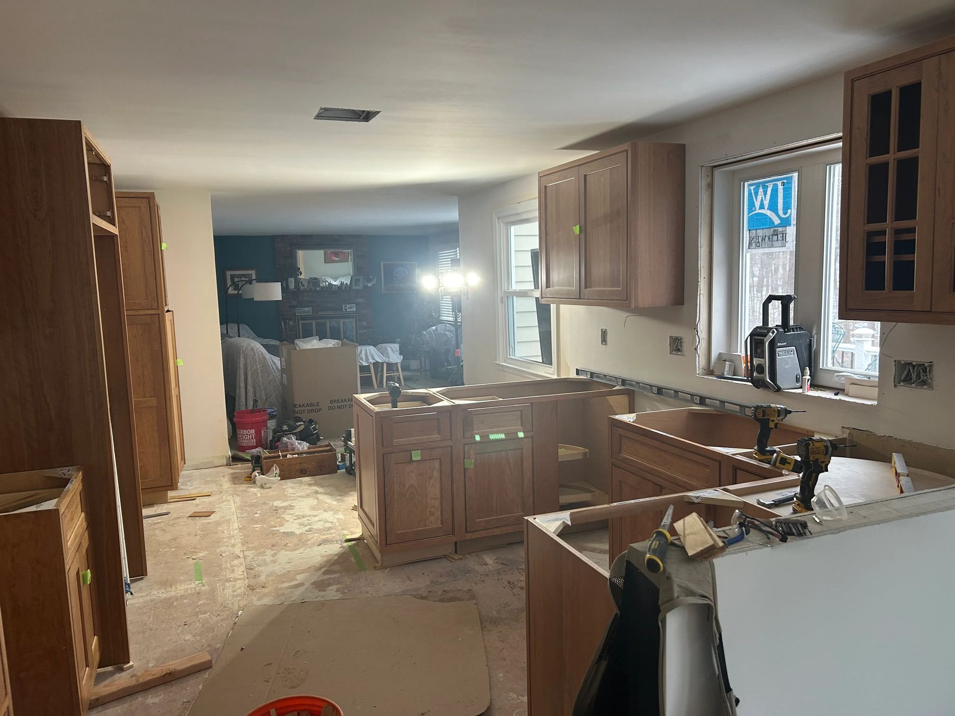 A kitchen under construction with wooden cabinets and a window.