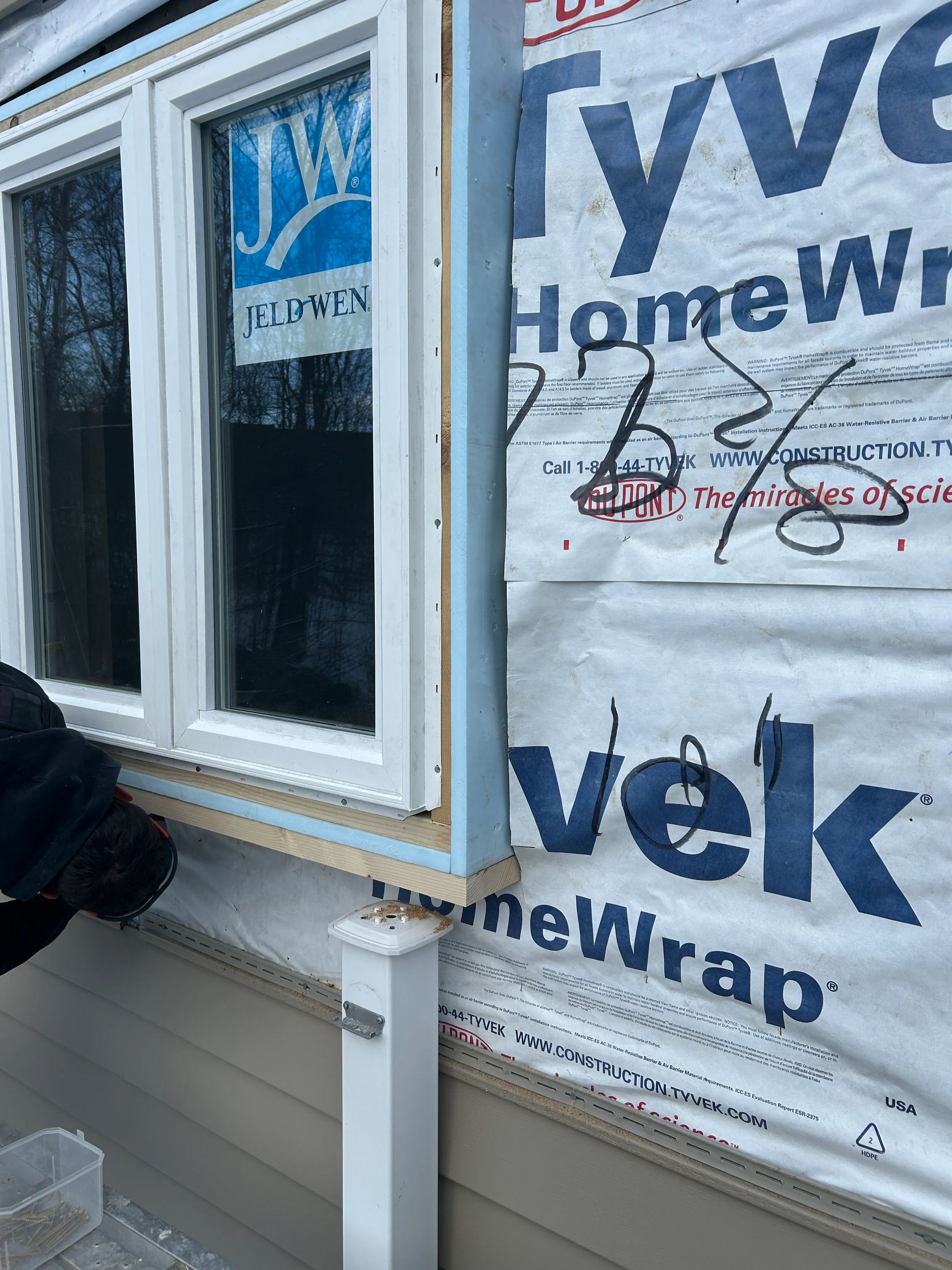 A person is installing a window on the side of a house.