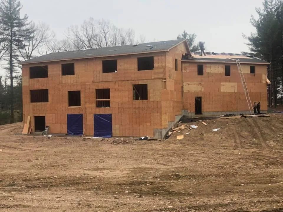 A large house is being built in a dirt field.