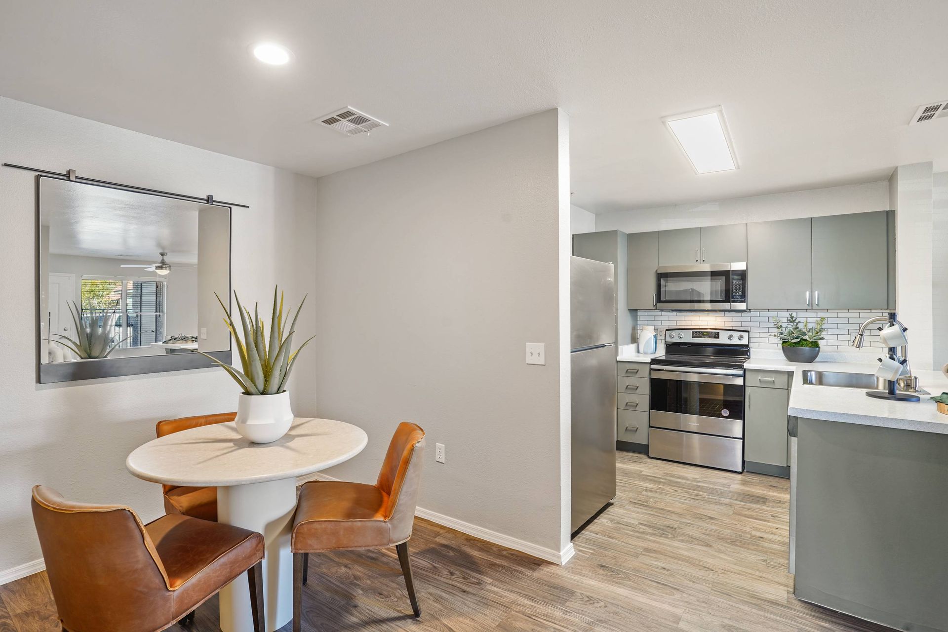 Dining area with round table and brown chairs next to the modern gray kitchen.
