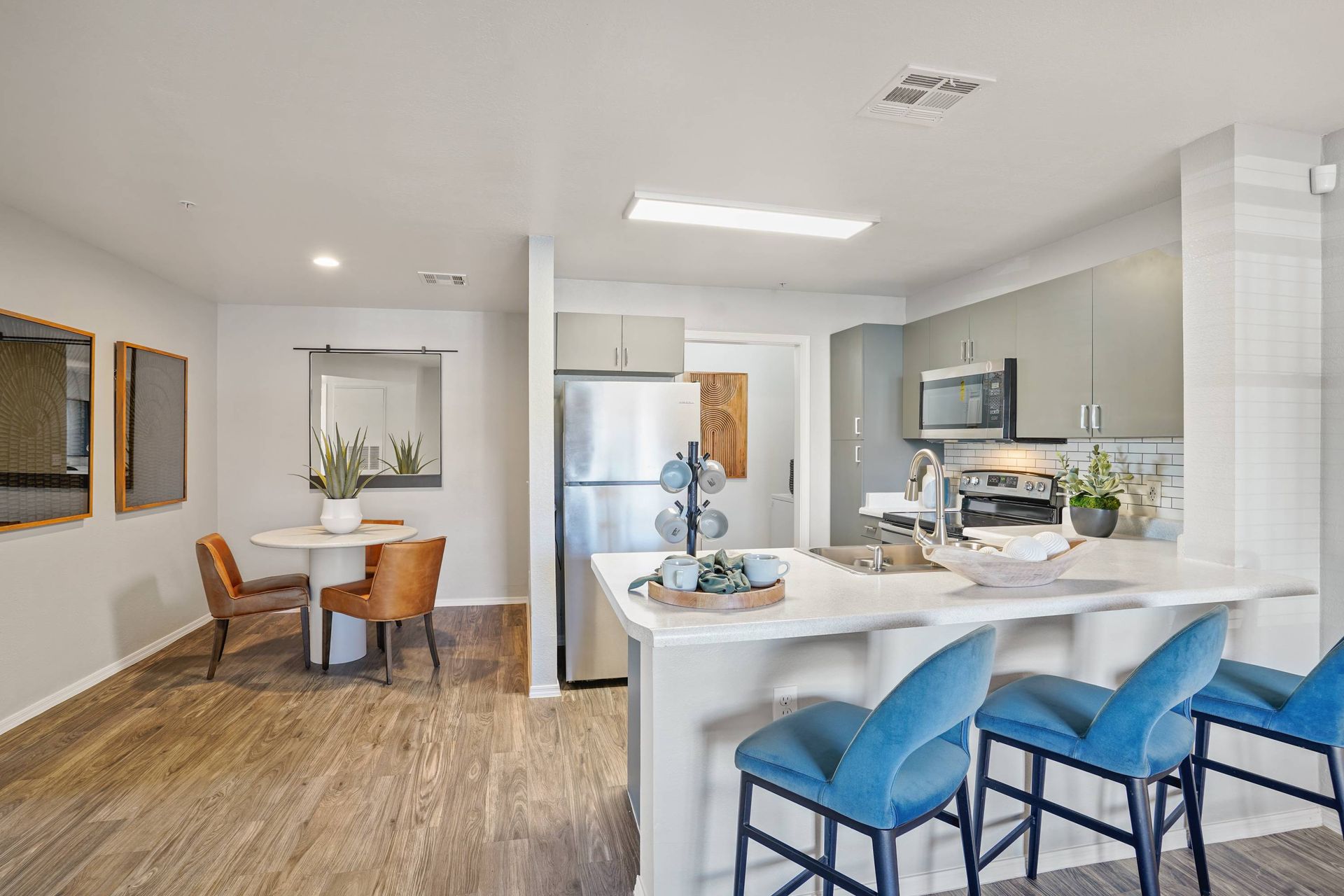 Open-concept apartment kitchen with island, stainless steel appliances, and a small dining area.