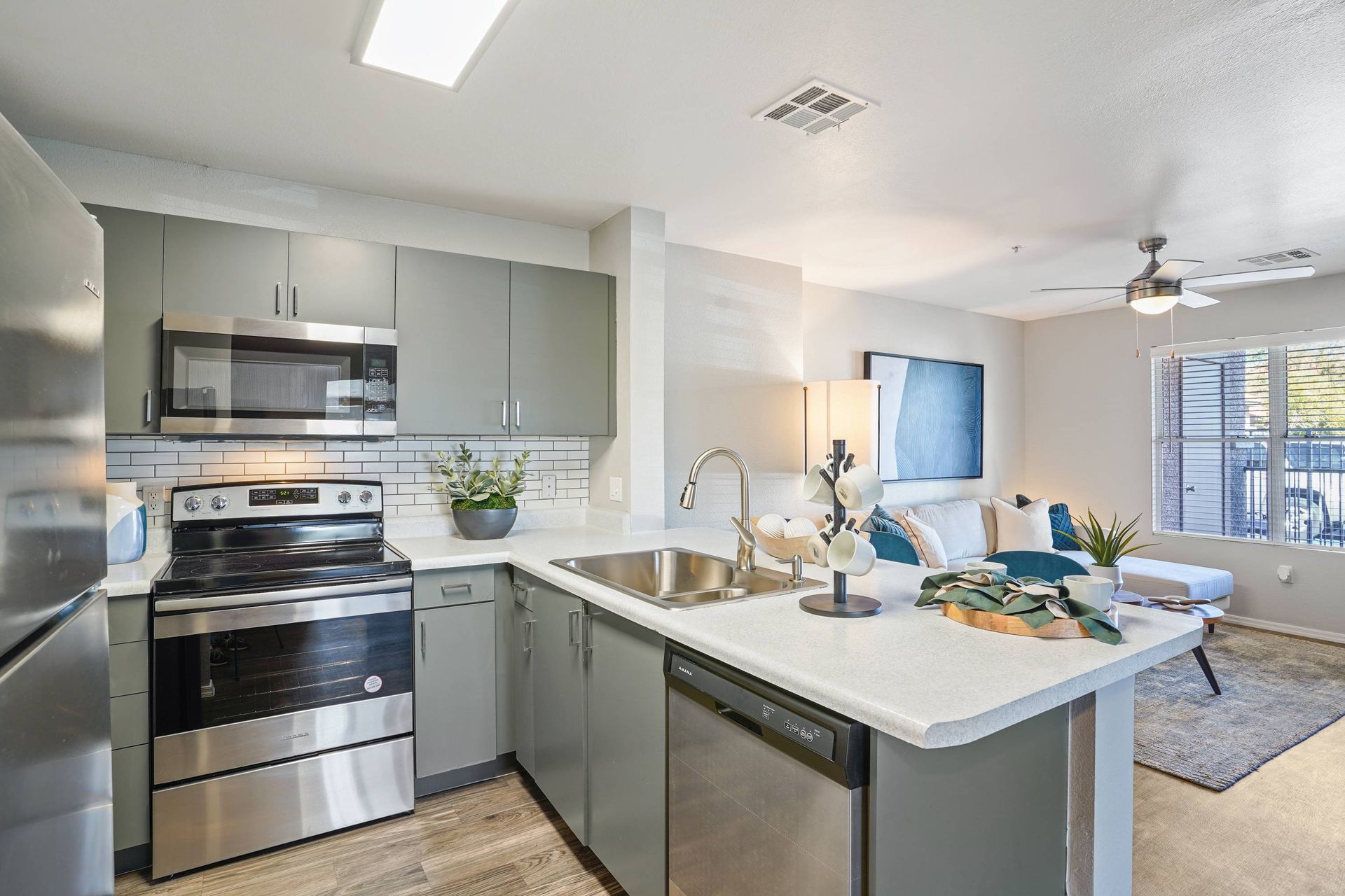 Open-concept kitchen with gray cabinets, stainless appliances, and a central island.