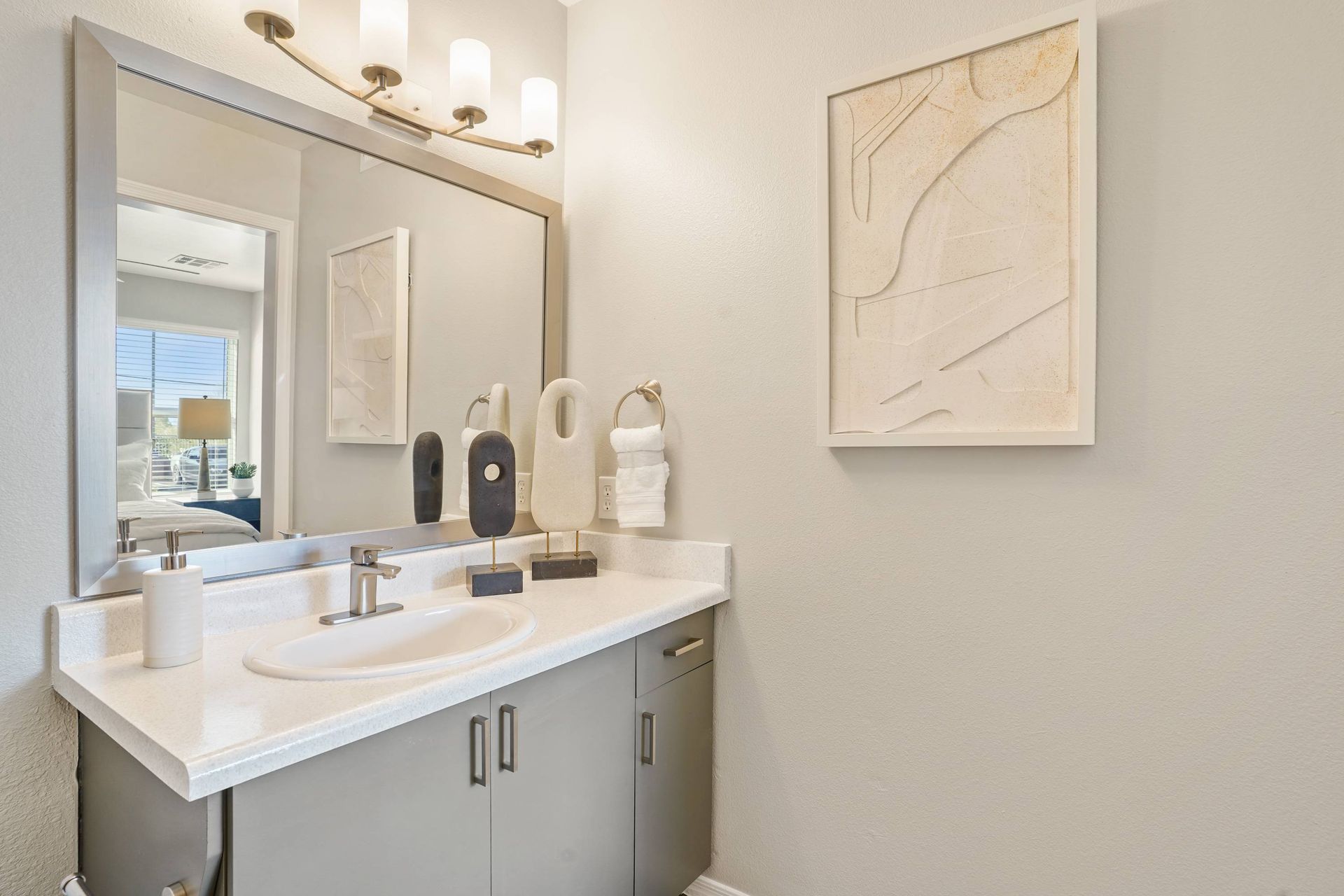 Bathroom vanity with sink, countertop, large mirror, and decorative accessories.