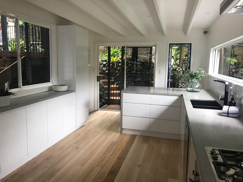 Kitchen With White Cabinets And Wooden Floor — Kitchen Cabinets in Ballina, NSW