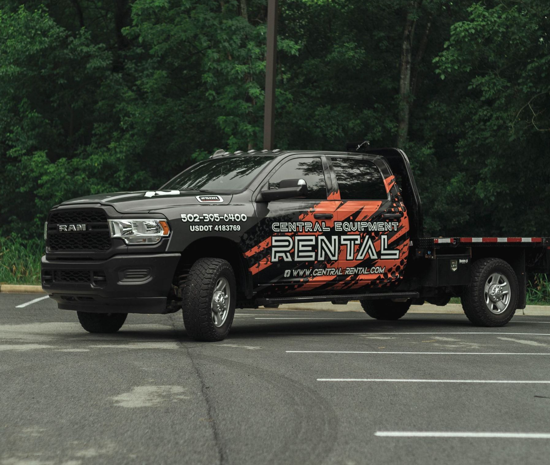 A black rental truck is parked in a parking lot